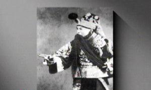 京剧老生剧照(头戴缀绒球盔头、挂白色长髯、深蓝绣云纹戏服、白色水袖,作指点身段);取自央视《跟我学》「前四大须生——高庆奎」页内配图,原页无题注故不指认剧目(已裁去左下角CCTV.com水印)