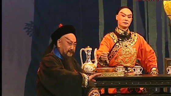 京剧《廉吏于成龙》演出照:对饮议事——二人对坐桌案,案上陈青花酒壶与酒杯
